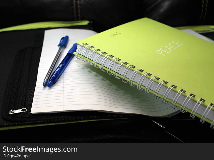 Green Spring Bind Book Beside 2 Blue Pens