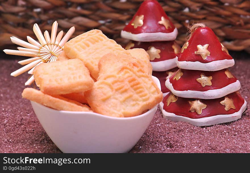 A bowl of cookies with Christmas decorations on a table. A bowl of cookies with Christmas decorations on a table.