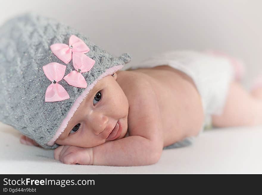 A newborn baby wearing a wool cap with pink bows. A newborn baby wearing a wool cap with pink bows.