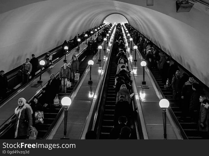 A view in a subway escalator with commuters on and other passengers in black and white. A view in a subway escalator with commuters on and other passengers in black and white.