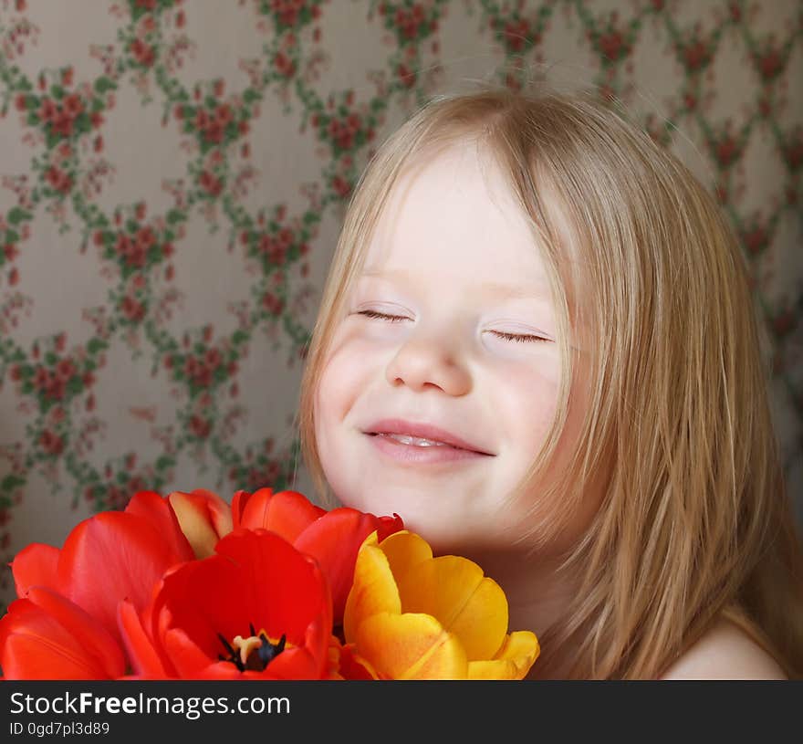 A little smiling girl with red and yellow tulip flowers. A little smiling girl with red and yellow tulip flowers