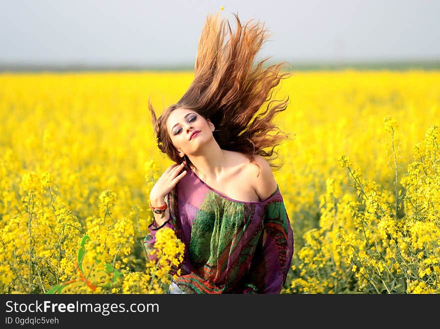 Portrait of Young Woman With Yellow Flowers in Field