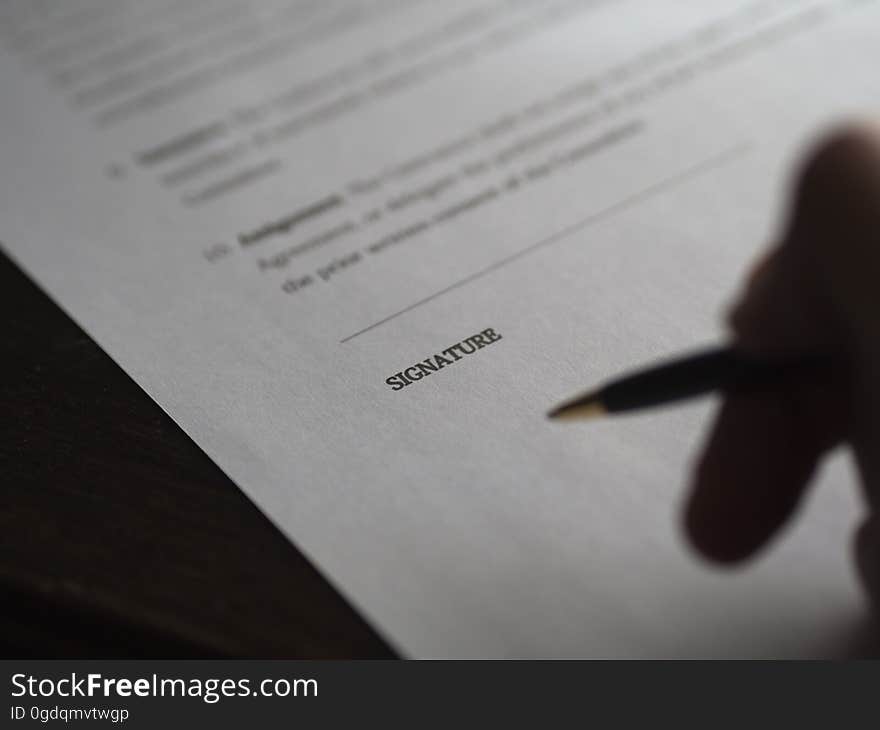 Closeup of a person signing paperwork.