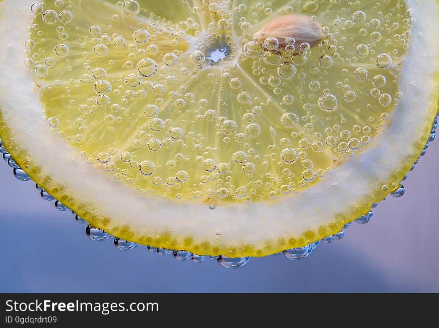 A slice of yellow lemon in a glass of carbonated water. A slice of yellow lemon in a glass of carbonated water.