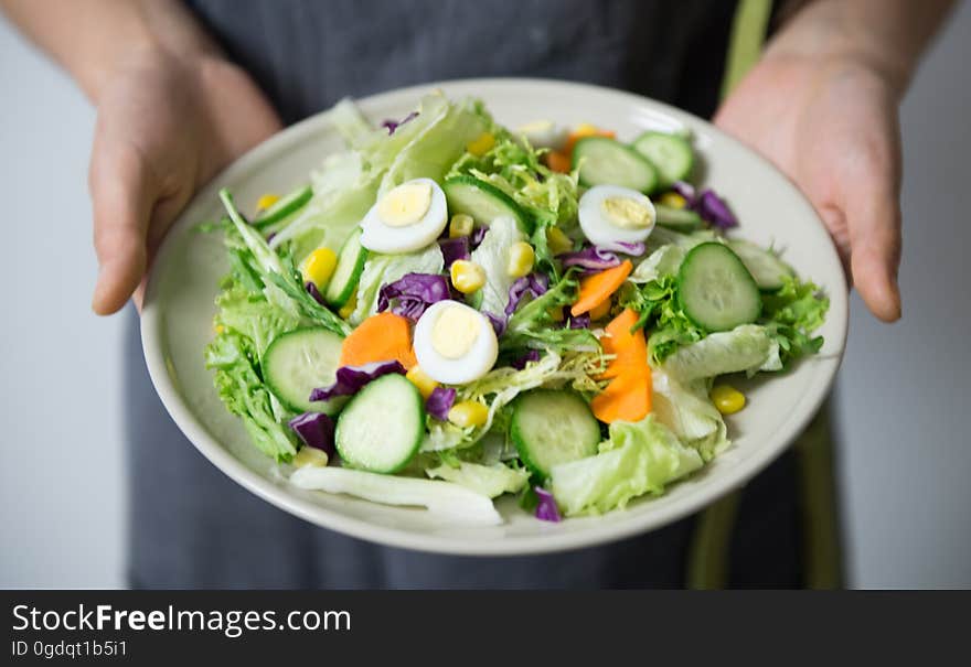 A person holding a plate with egg salad.