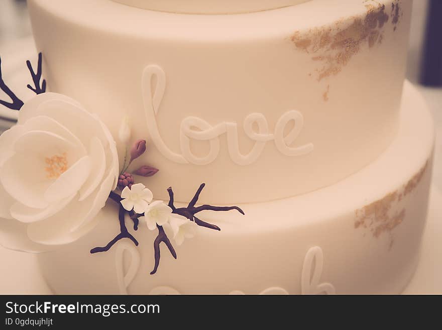 A white fondant cake with the writing "love" on the side.