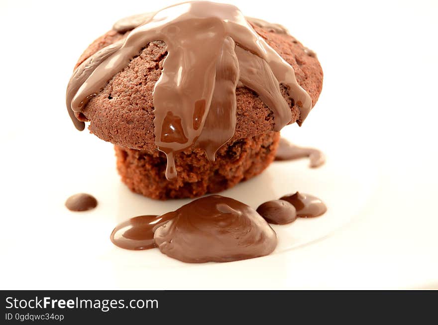 A rich chocolate muffin with chocolate icing isolated on white.