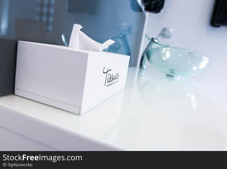 A bathroom sink with box of tissues next to it. A bathroom sink with box of tissues next to it.