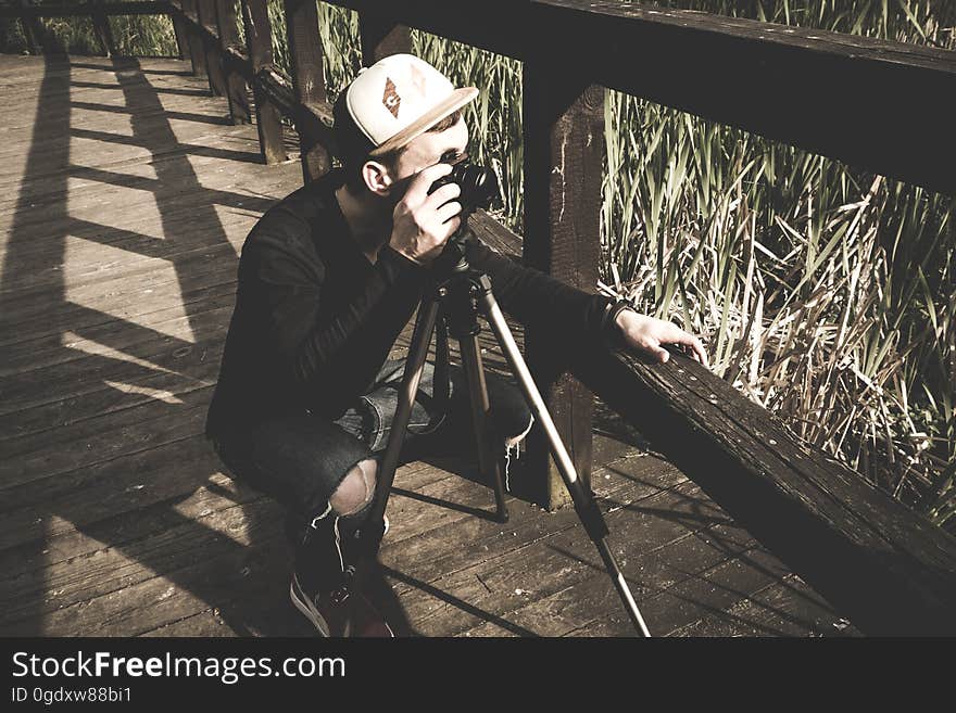 A photographer with a camera on a tripod taking a photo from a bridge. A photographer with a camera on a tripod taking a photo from a bridge.