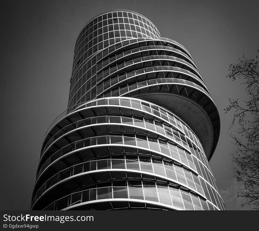 Black and white view looking to top of curved tall modern office tower building. Black and white view looking to top of curved tall modern office tower building.