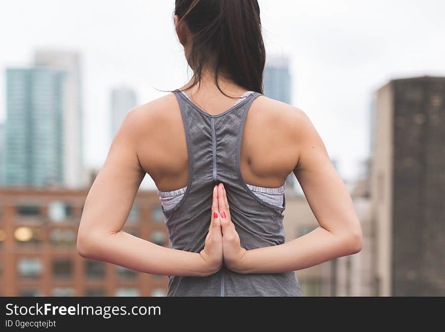 A woman doing the Pashchima Namaskarasana yoga pose with hands behind back in reverse prayer position.