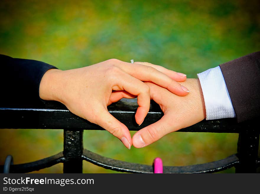 A couple making a heart shape with their hands to celebrate their engagement.