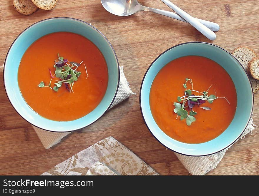 Bowls of creamy tomato soup on a wooden table.