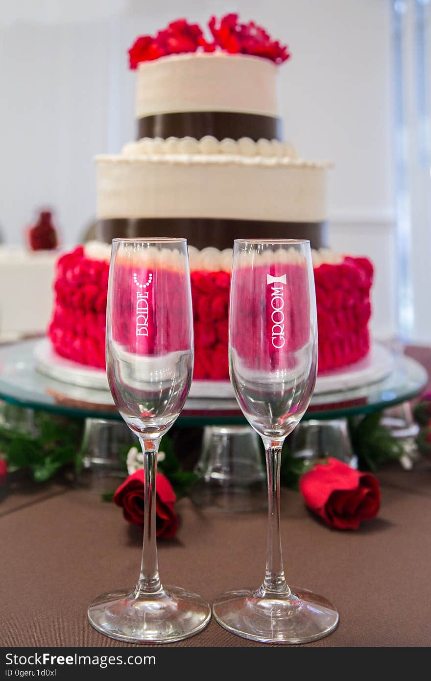 A pair of champagne glasses for the bride and the groom and a wedding cake. A pair of champagne glasses for the bride and the groom and a wedding cake.