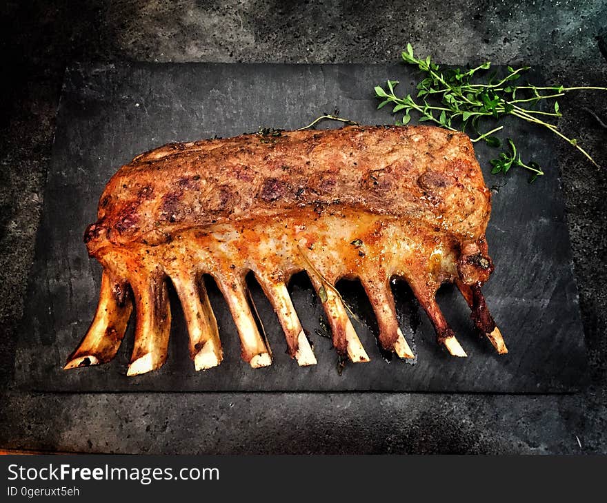 Rib of beef cooking over a barbecue, looking brown and well done, with sprigs of herb (rosemary or thyme) placed behind. Rib of beef cooking over a barbecue, looking brown and well done, with sprigs of herb (rosemary or thyme) placed behind.