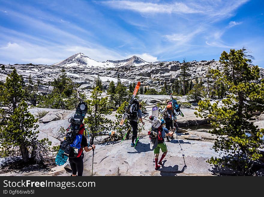 Group of People Hiking With Snowboards Under Blue Cloudy Sky