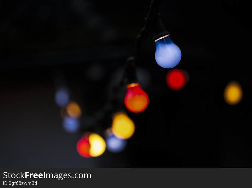 Blurred colored filament light bulbs with envelope in red, yellow orange, blue and brown, black background,. Blurred colored filament light bulbs with envelope in red, yellow orange, blue and brown, black background,