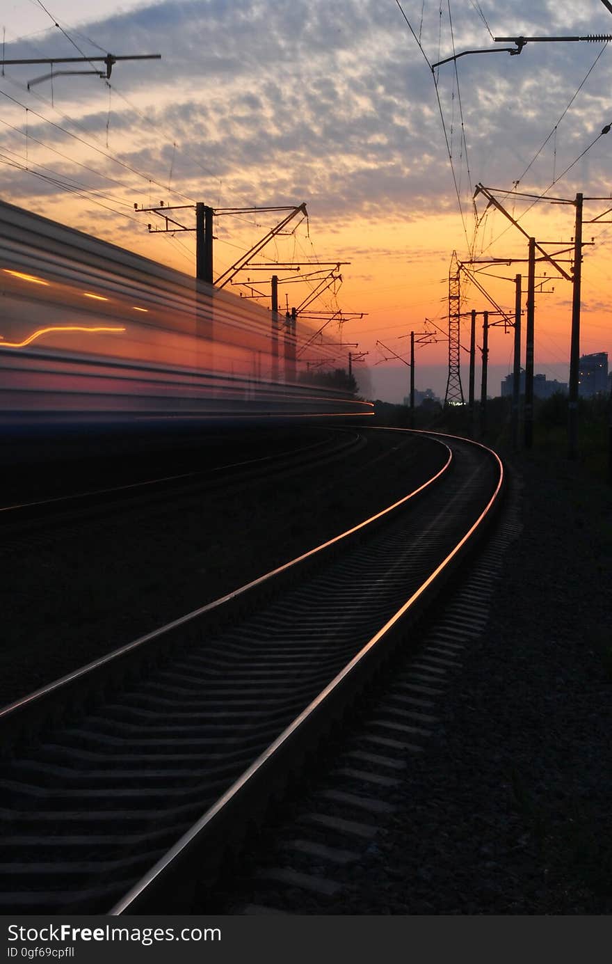 Rail Road Under Gray and Orange Cloudy Sky during Sunset