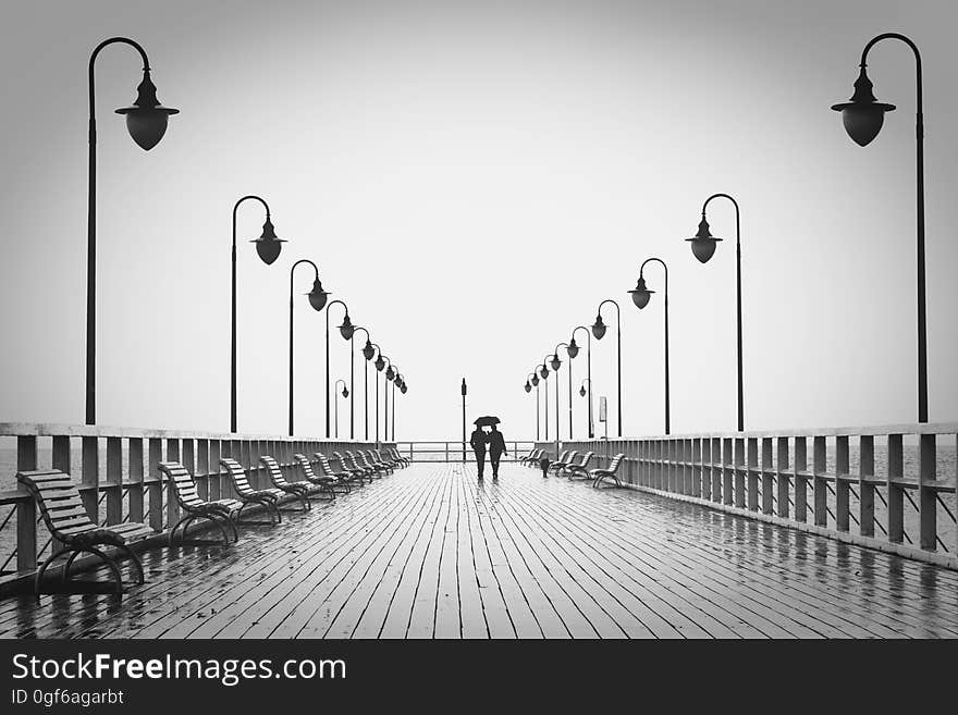 A couple walking on a pier in the rain. A couple walking on a pier in the rain.