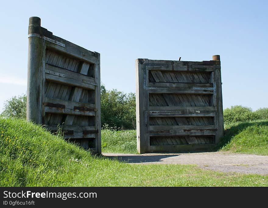 An opened wooden gate on a rural road.