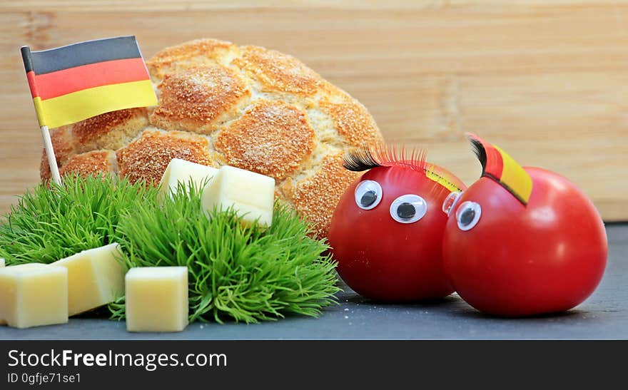 A pair of tomatoes wearing the German flag colors with a football shaped bread. A pair of tomatoes wearing the German flag colors with a football shaped bread.