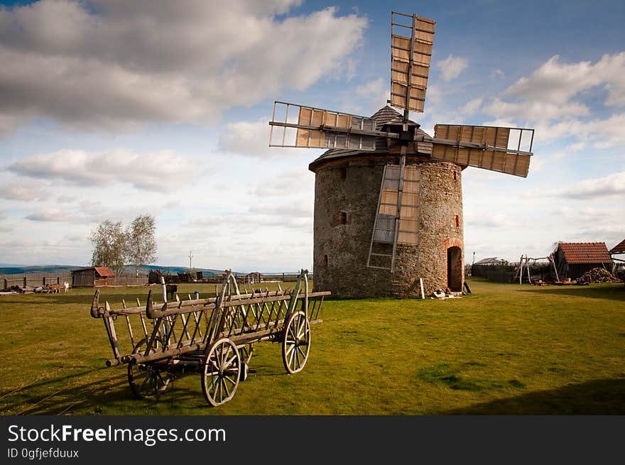 Wooden Windmill Near Wooden Carriage during Daytime