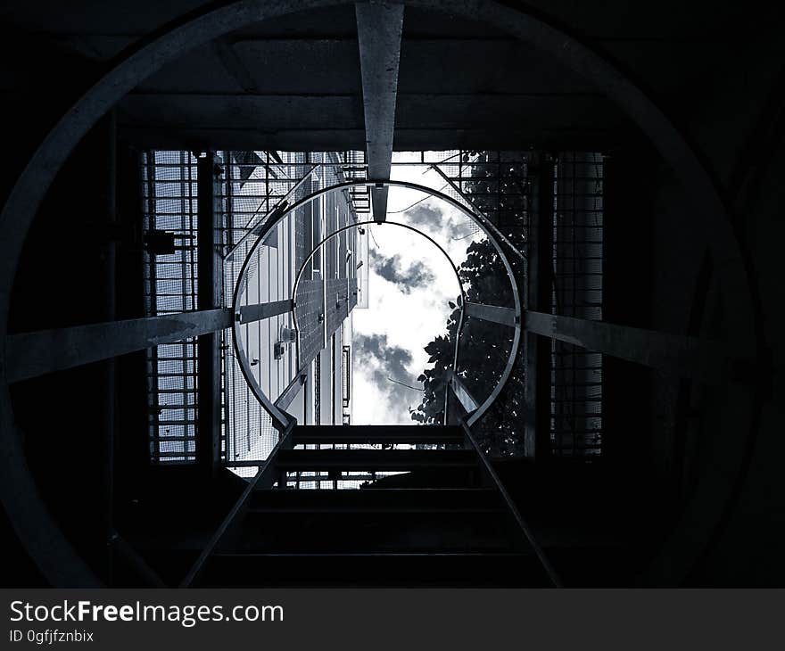 A view from inside a manhole with a ladder rising up to the sky. A view from inside a manhole with a ladder rising up to the sky.