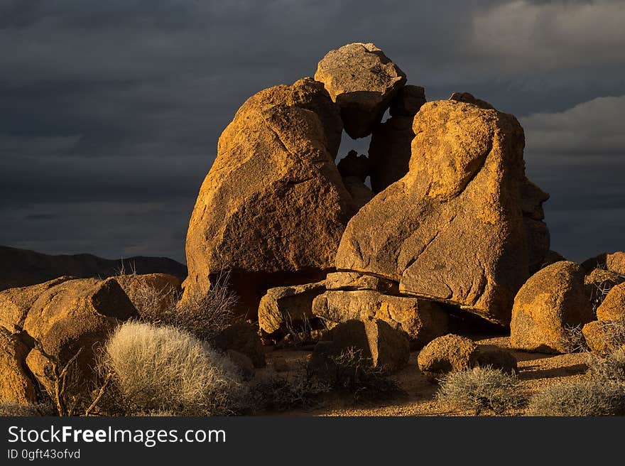 Rock Formed Person Under Heavy Clouds during Daytime