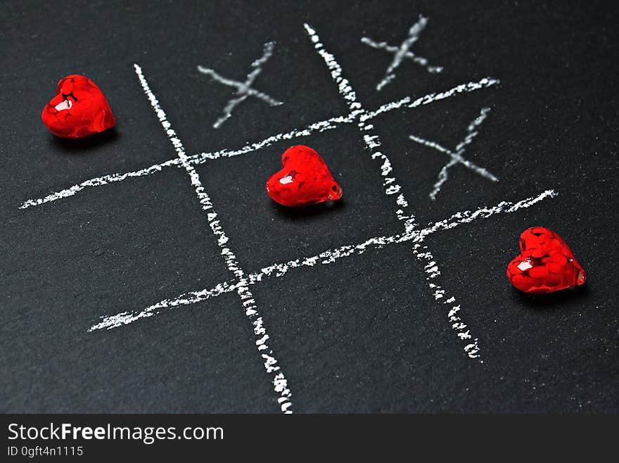 A close up of a chalkboard with a game of tic-tac-toe with hearts instead of naughts. A close up of a chalkboard with a game of tic-tac-toe with hearts instead of naughts.