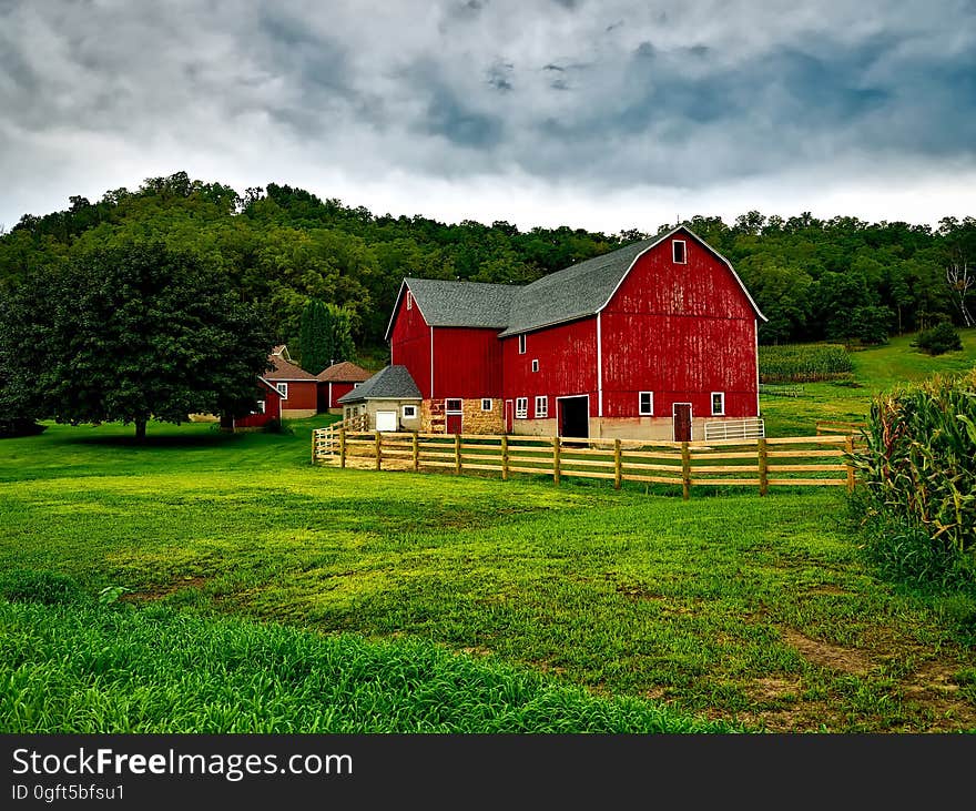 A typical red barn in the middle of green fields.