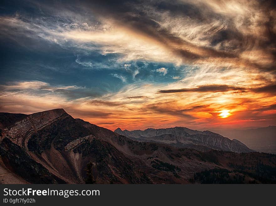 A mountain range with the sun setting over it. A mountain range with the sun setting over it.