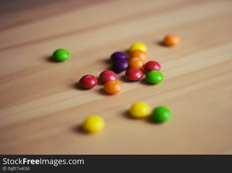 A bunch of colorful Skittles candies on wood background.