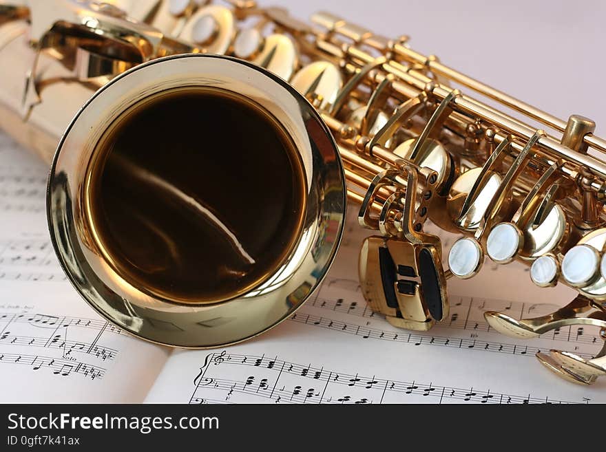 A saxophone on top of sheet music. A saxophone on top of sheet music.