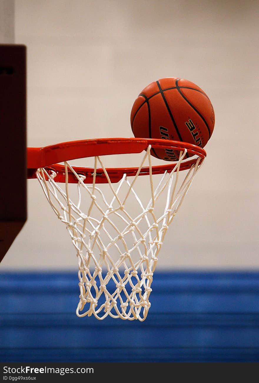 A basketball hovers on the rim of a net. A basketball hovers on the rim of a net.