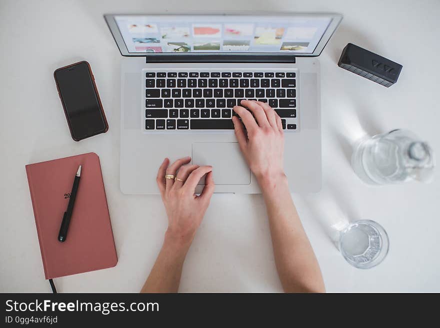 Hands typing on laptop and office equipment on the table.