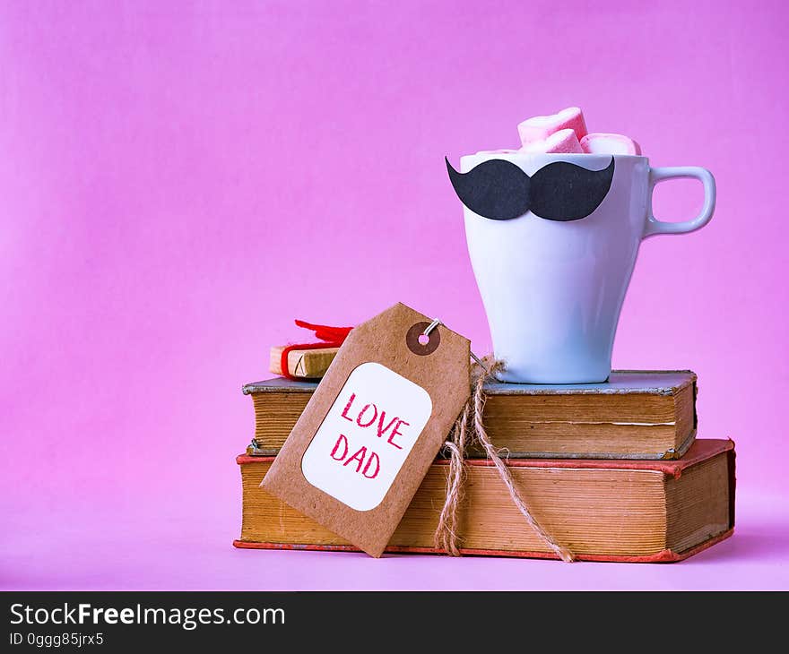 Father`s day concept. LOVE DAD alphabet on stack of books, gifts, tea cup with black Mustache on pink background