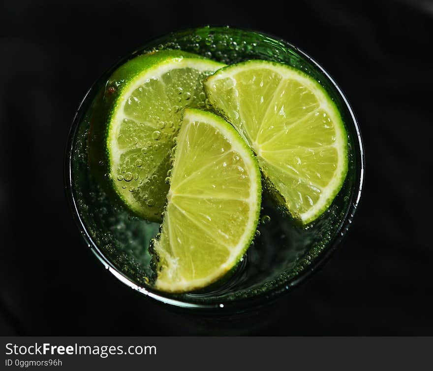 A glass with slices of green lime. A glass with slices of green lime.