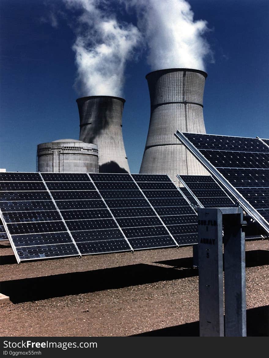 A solar farm with cooling towers in the background. A solar farm with cooling towers in the background.