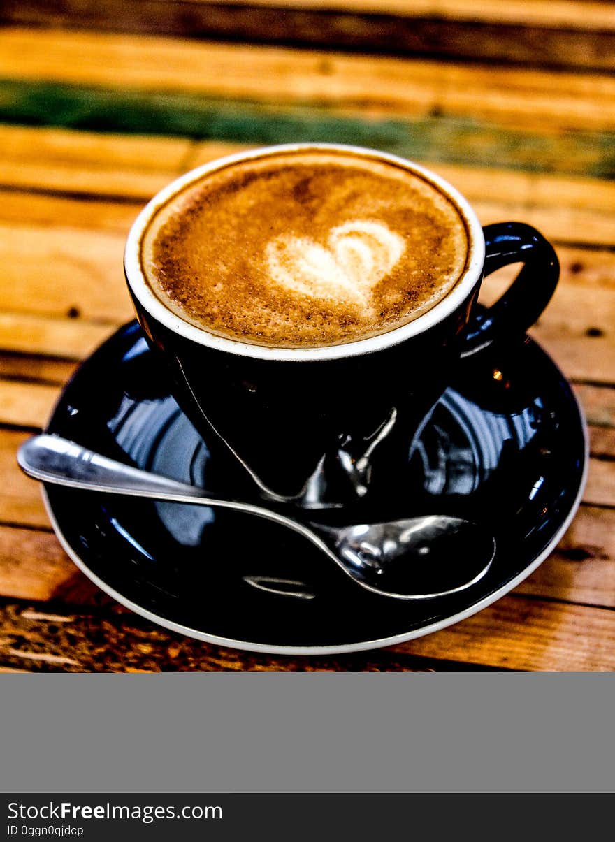 A latte in a black mug on a wooden table.