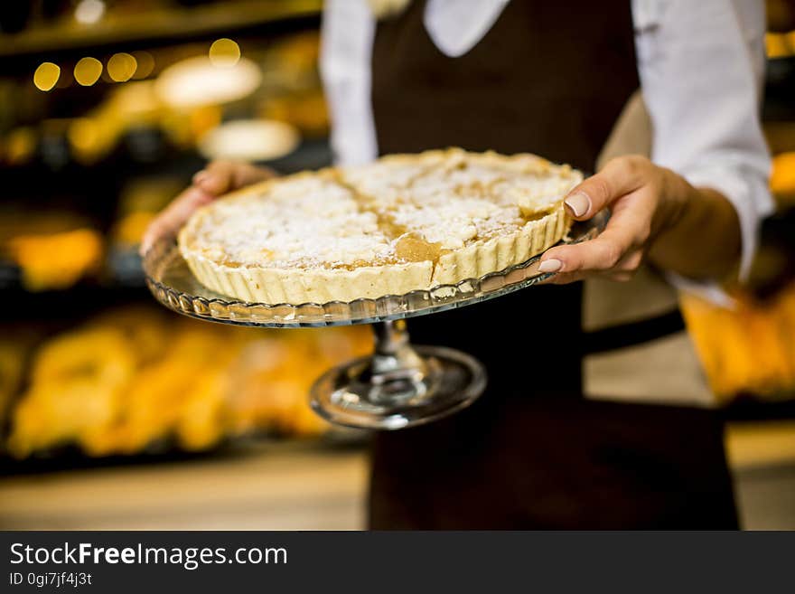 Bakery female worker posing with apple tart in bakery