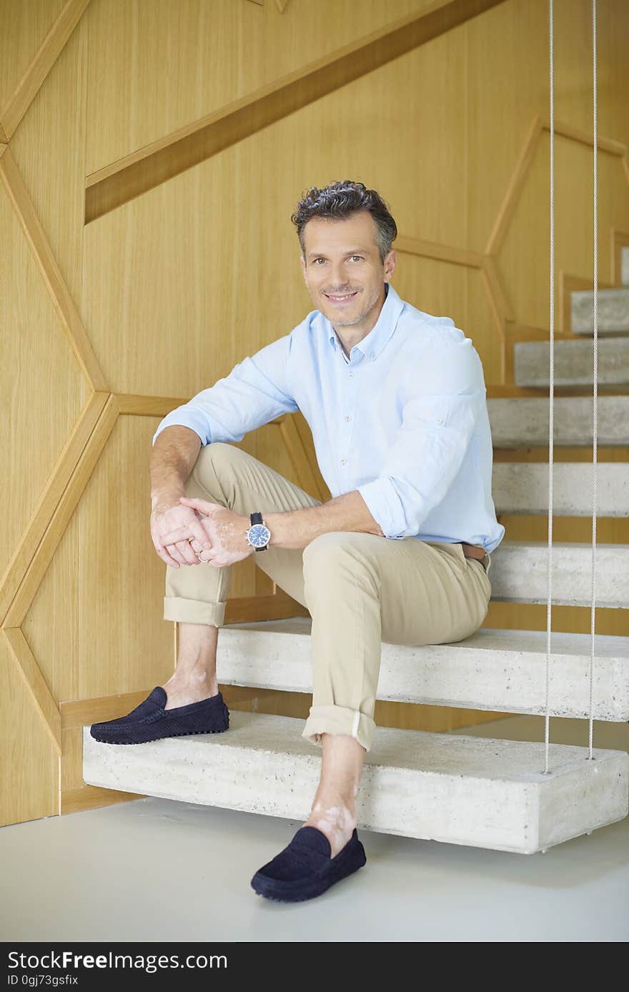 Full length shot of a smiling casual man sitting on stairs at home and enjoy life. Full length shot of a smiling casual man sitting on stairs at home and enjoy life.