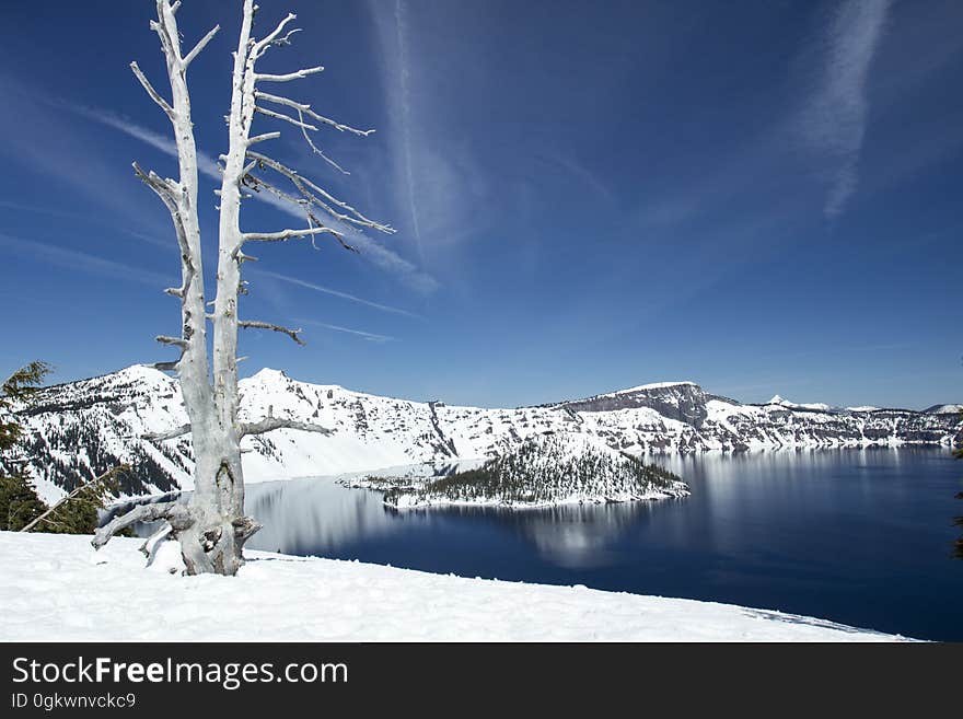 Deep blue lake with surrounding snow and a view of Wizard Island. Deep blue lake with surrounding snow and a view of Wizard Island.