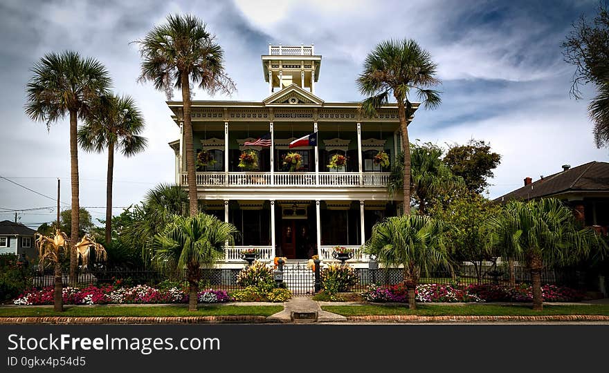 White Painted Structure With Green Palm Trees in the Front