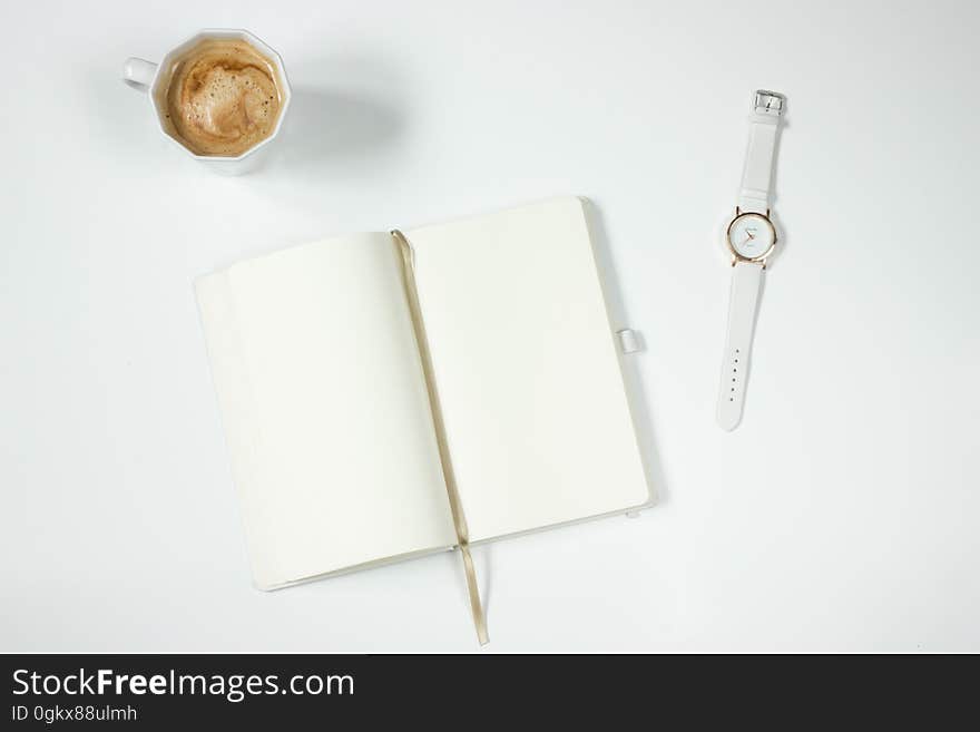 White Leather Strap Silver Round Analog Watch Next to Notebook