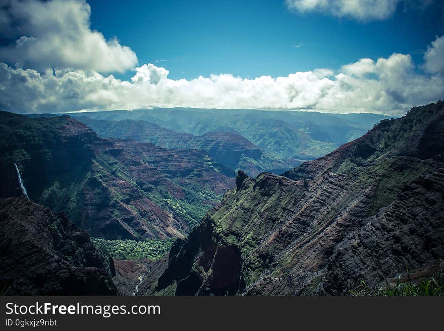 Scenic view through mountains at a distant mountain range and a blue sky with clear weather clouds. Scenic view through mountains at a distant mountain range and a blue sky with clear weather clouds.