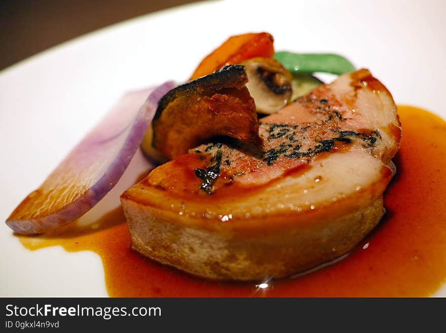 A plate of duck liver with vegetable garnish.