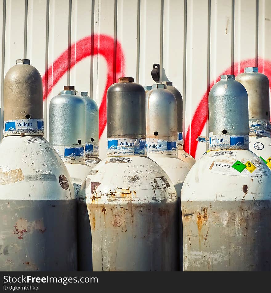 Gray Steel Gas Tanks Near White Steel Wall during Daytime