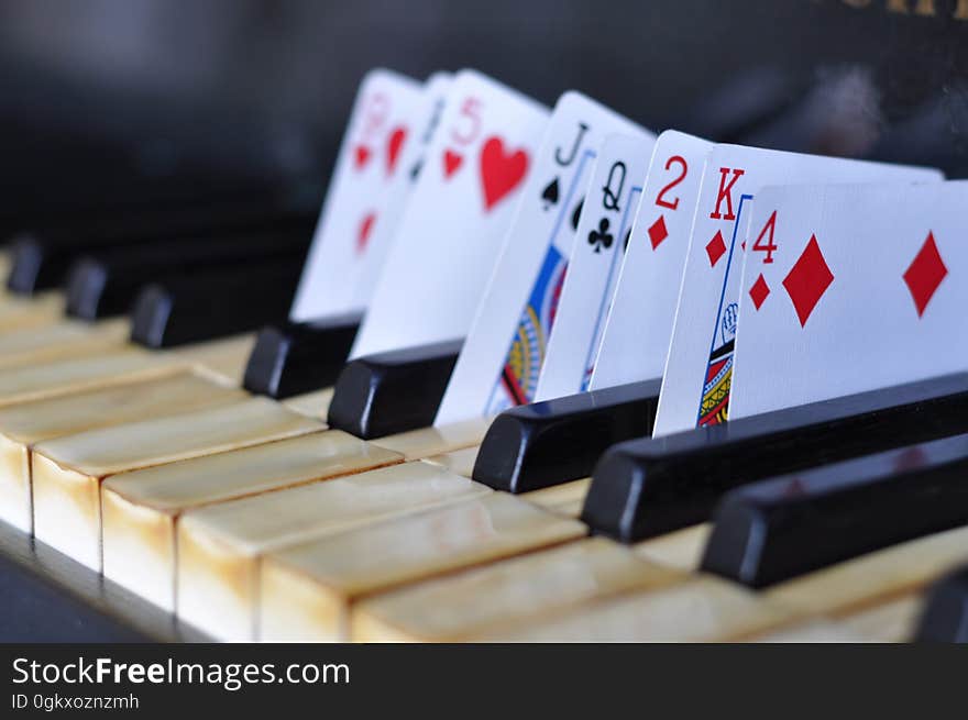 Closeup of playing cards in between piano keys.