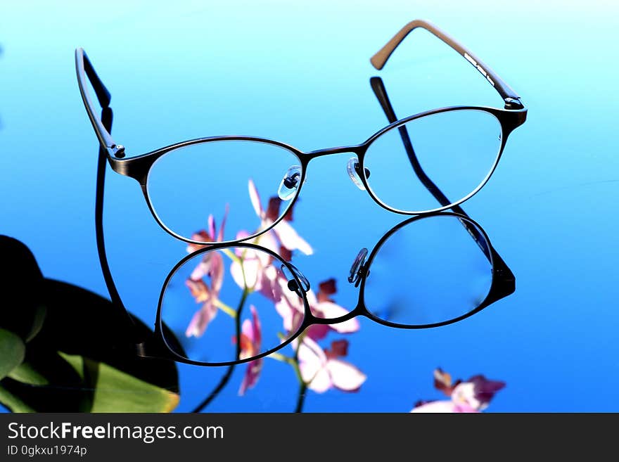 A pair of eyeglasses on a mirror surface. A pair of eyeglasses on a mirror surface.