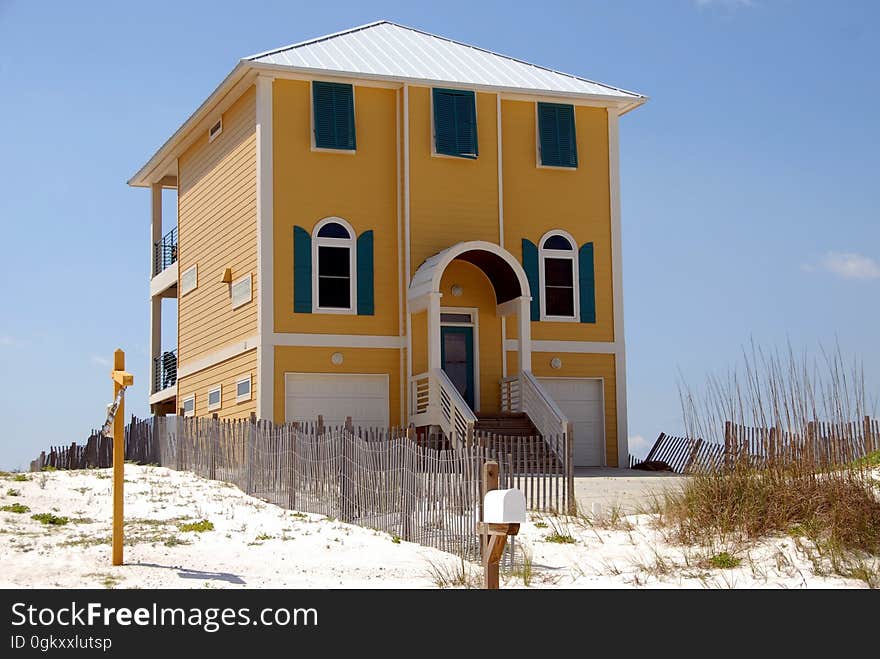 Tall modern home by sandy beach with blue sky background. Tall modern home by sandy beach with blue sky background.